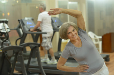 Older woman does stretching exercises in a gym