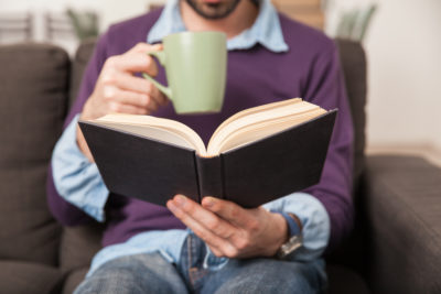 Man relaxing with book and mug of tea