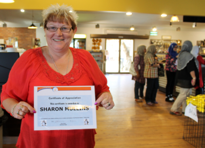 Volunteer Sharon holds up her certificate of appreciation
