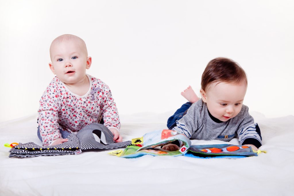 Two babies on the floor playing with cloth books