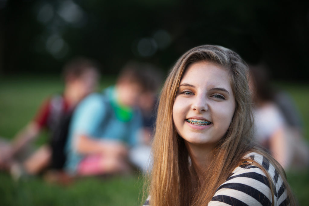 Teenage girl outside smiles at camera