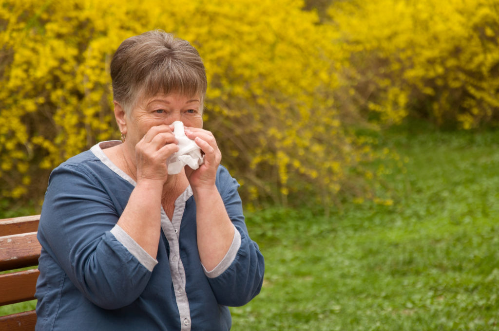 Person with allergies in park blowing her nose
