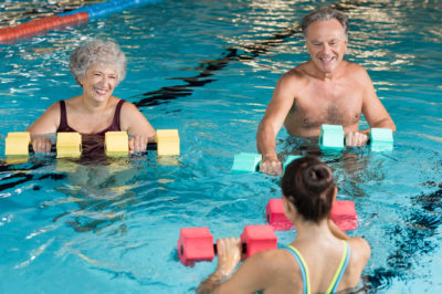 Three people doing exercises with floats in a pool