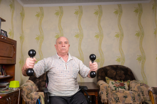 Man in wheelchair exercising with dumbbells at home