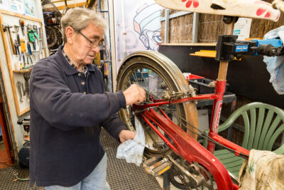 Man cleaning bike wheel and chain in the Men's Shed